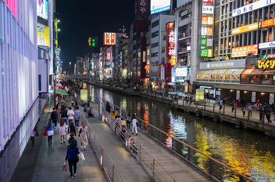 People on illuminated street in city at night