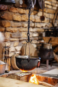 Cooking in an old cast-iron boiler on a fire against a brick wall, postcard, close-up