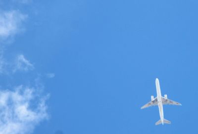 Low angle view of airplane flying against clear blue sky