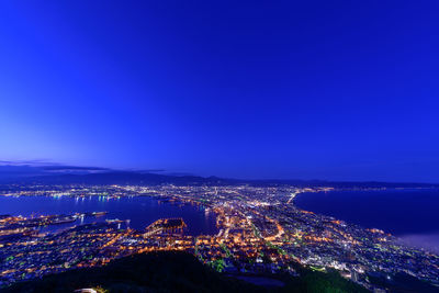 High angle view of illuminated buildings against blue sky