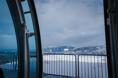 Scenic view of snowcapped mountains against sky seen through window