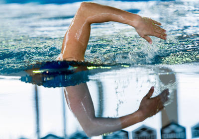 Cropped hand of mid adult woman swimming in pool