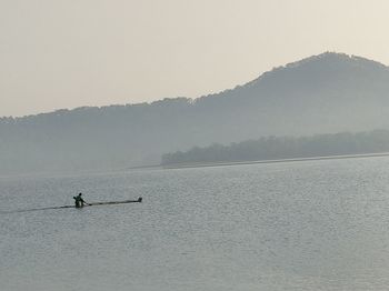 Silhouette person on lake against sky