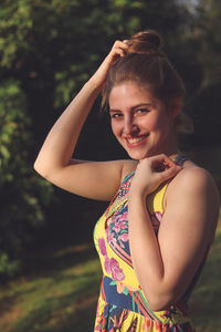 Portrait of smiling beautiful young woman standing on field