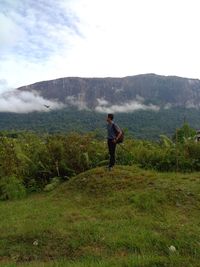 Rear view of man looking at mountains against sky