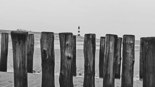 Wooden posts on fence against clear sky