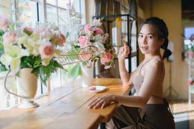 Portrait of young woman sitting on table