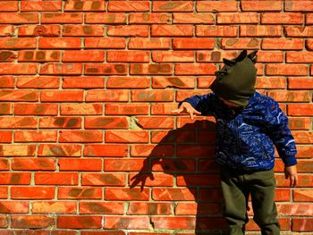 Full length of person standing against brick wall