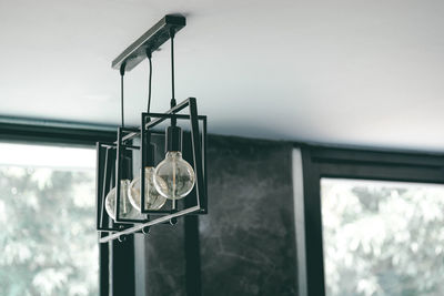 Low angle view of light bulbs hanging from glass window