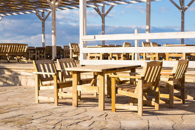 Empty chairs and tables in cafe against sky