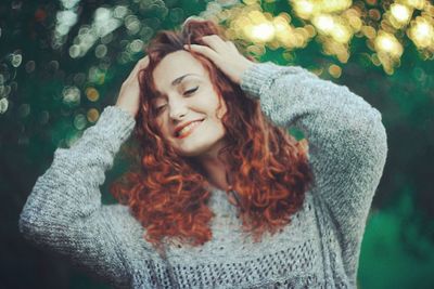 Close-up of young woman with hands in hair