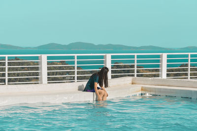Man relaxing in swimming pool against sea