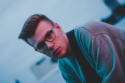 Close portrait of young man wearing eyeglasses sitting outdoors