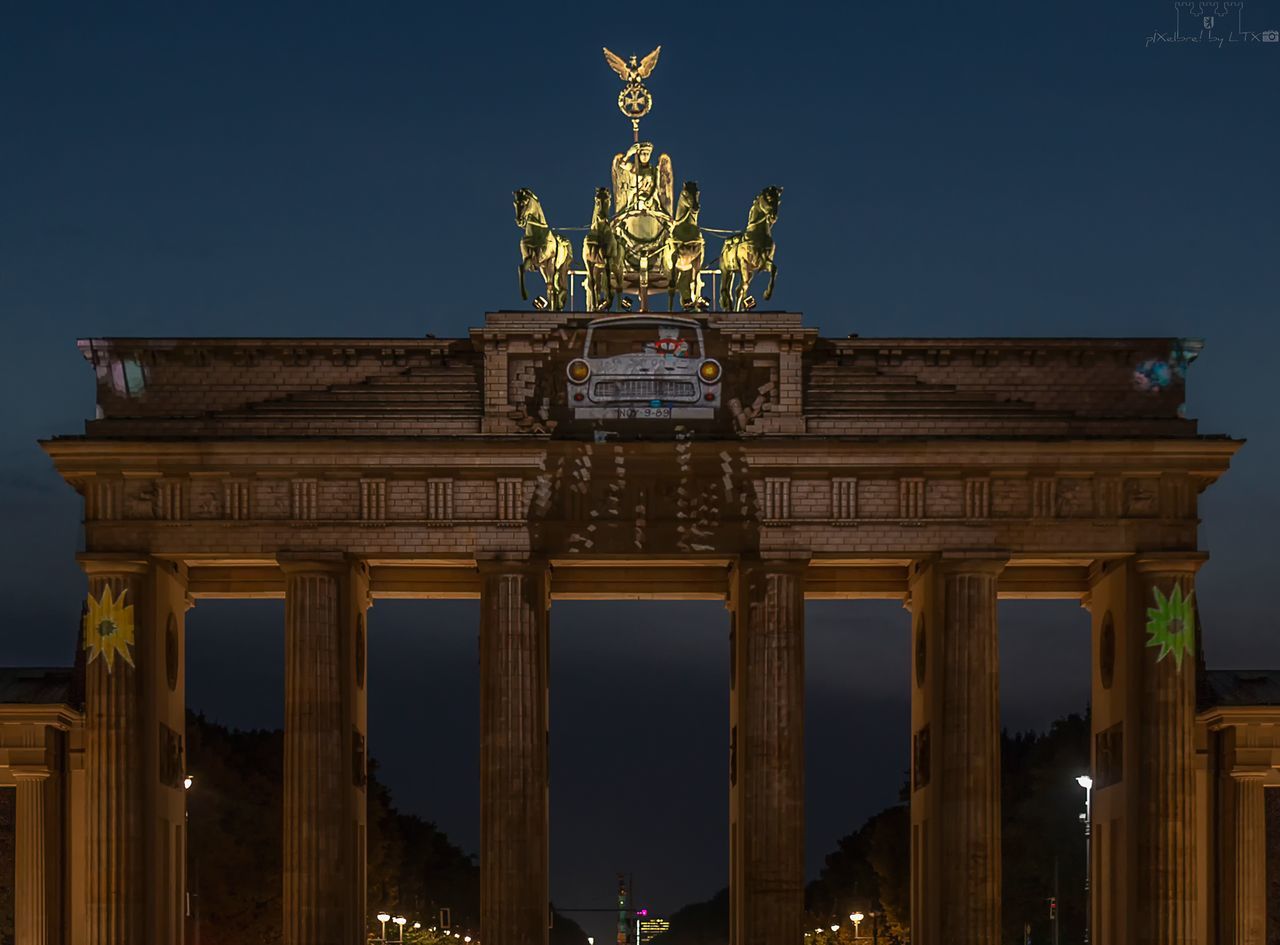 architecture, built structure, statue, city gate, architectural column, history, text, sculpture, travel destinations, tourism, illuminated, outdoors, building exterior, night, memorial, low angle view, sky, clear sky, no people, city