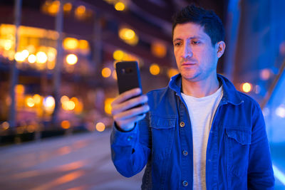 Portrait of young man using mobile phone at night