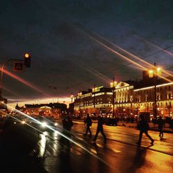 Illuminated city street against sky at night