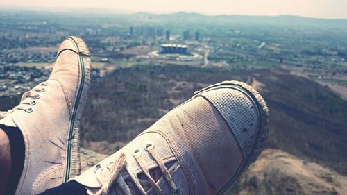 Low section of person wearing canvas shoe in front of mountain