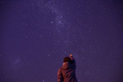 Rear view of person standing against star field at night
