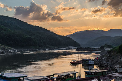 Scenic view of river by mountains against sky during sunset