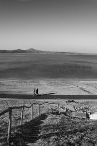 Woman walking on road by sea