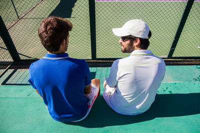 Tennis players sitting against net at court