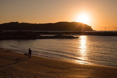 Silhouette person on beach against sky during sunset