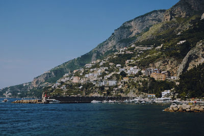 Scenic view of sea by buildings against clear sky