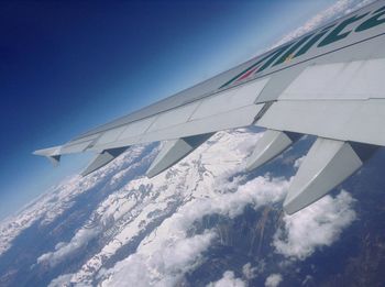 Low angle view of airplane wing against blue sky