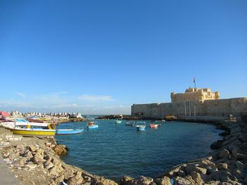 Boats in sea against buildings in city