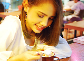 Woman stirring drink while sitting on table