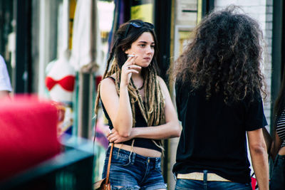 Young woman looking away while standing outdoors