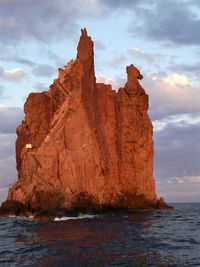 Rock formation by sea against sky