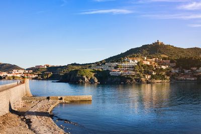 Scenic view of sea and buildings in town against sky