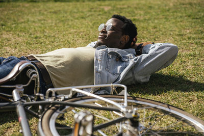 Young man with bicycle, relaxing, lying on grass