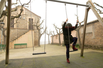 Young girl sheltered in an abandoned swing set with hood, unrecognisable.