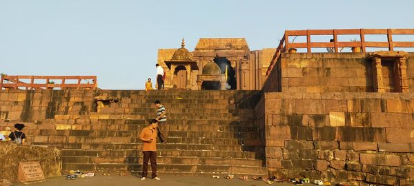 Rear view of people standing against clear sky