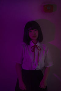 Portrait of young woman standing against wall