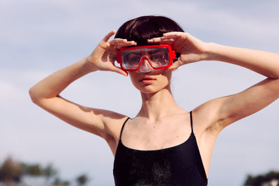Low angle view of woman holding sunglasses against sky