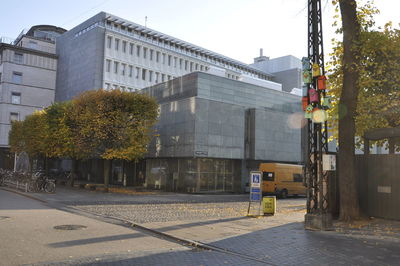 Street by buildings in city against clear sky