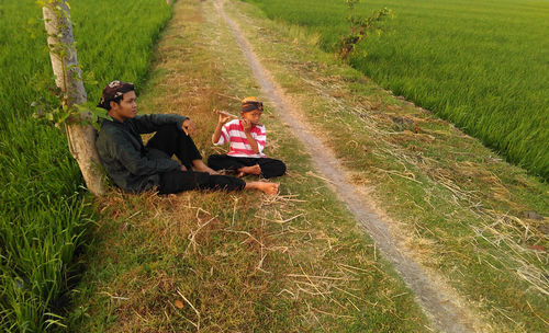 Father and son sitting on footpath amidst farm