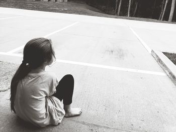 Rear view of girl sitting on footpath