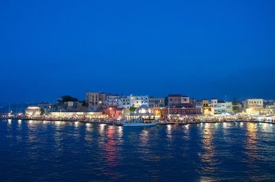 View of calm sea with illuminated buildings in background