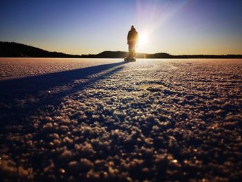 Silhouette person on beach against sky during sunset