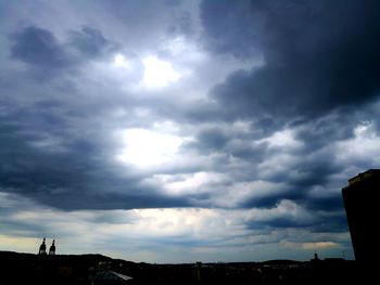 Silhouette of city against cloudy sky