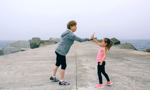 Grandmother and granddaughter giving high five at beach