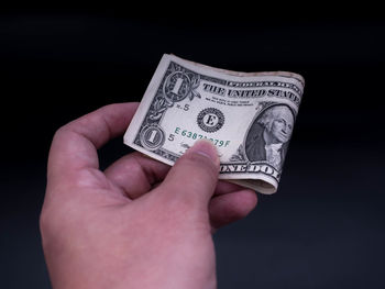 Close-up of hand holding paper over black background