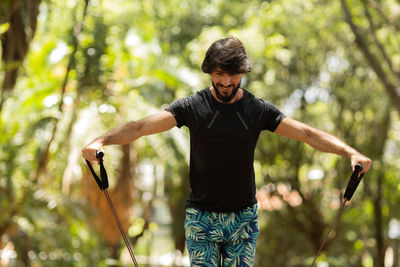 Man guy working out with elastic rubber bands at park outdoors.  additional sport equipment. 