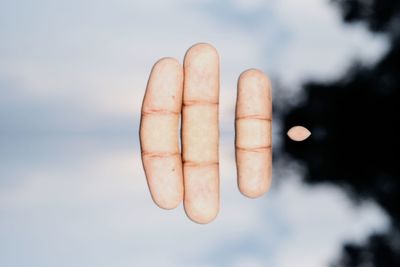 Close-up of human hand against sky