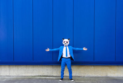 Full length of boy standing against blue wall