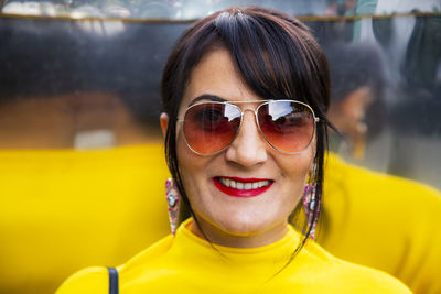 Fashionable mature woman wearing yellow top and sunglasses in city